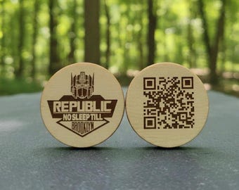 May include: Two round wooden tokens. One features a robot graphic and the text "REPUBLIC NO SLEEP TILL BROOKLYN". The other token has a QR code. Both tokens are light brown.