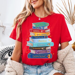 a woman wearing a red shirt with a stack of books on it