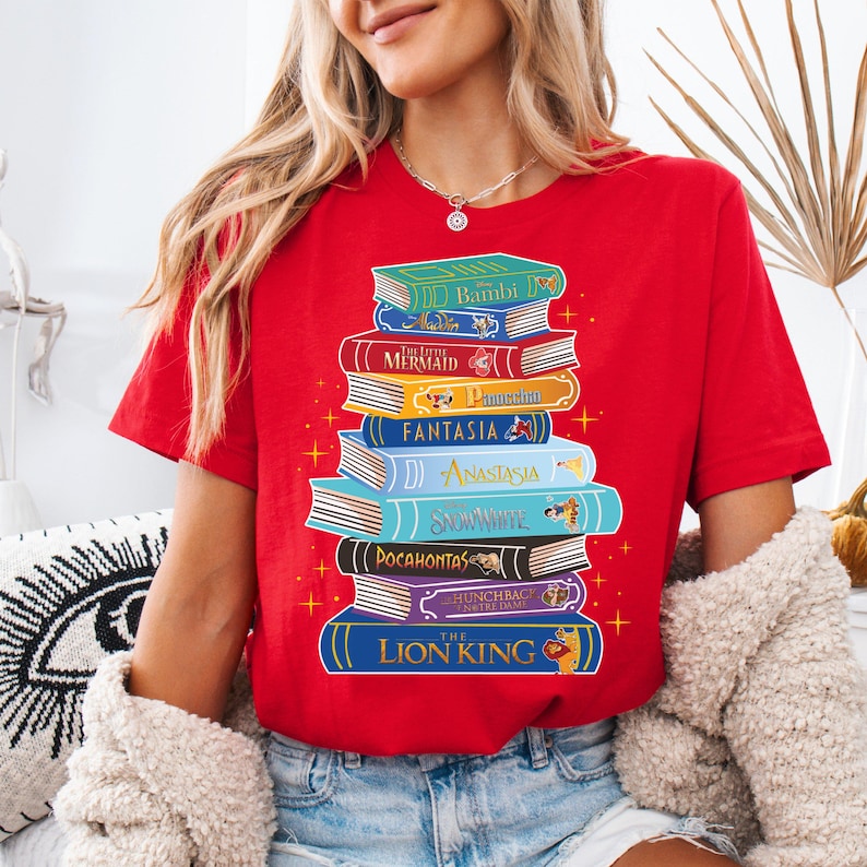 a woman wearing a red shirt with a stack of books on it