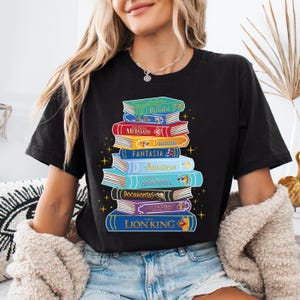 a woman wearing a black shirt with a stack of books on it
