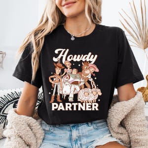 a woman wearing a black t - shirt with cartoon characters on it