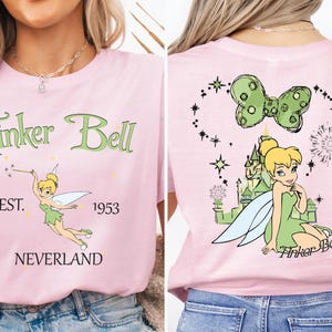 a woman wearing a pink shirt with tinkerbell on it