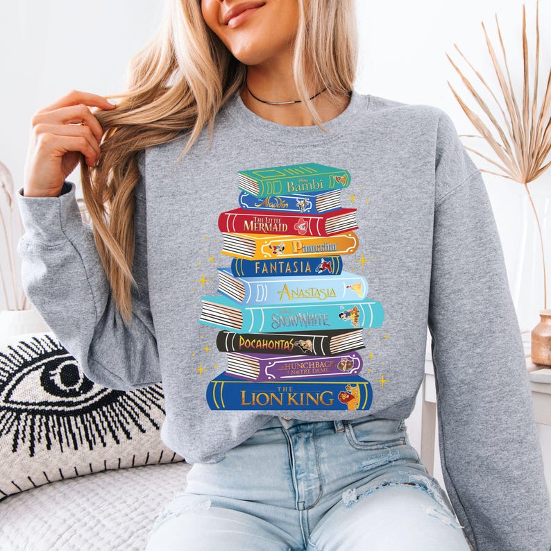 a woman wearing a sweatshirt with a stack of books on it