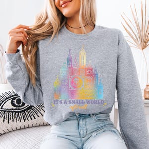 a woman wearing a sweatshirt that says it's a small world