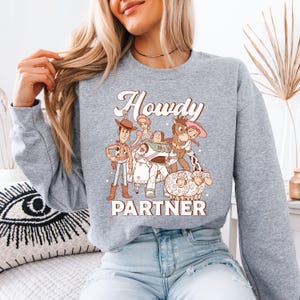 a woman sitting on a bed wearing a grey sweatshirt