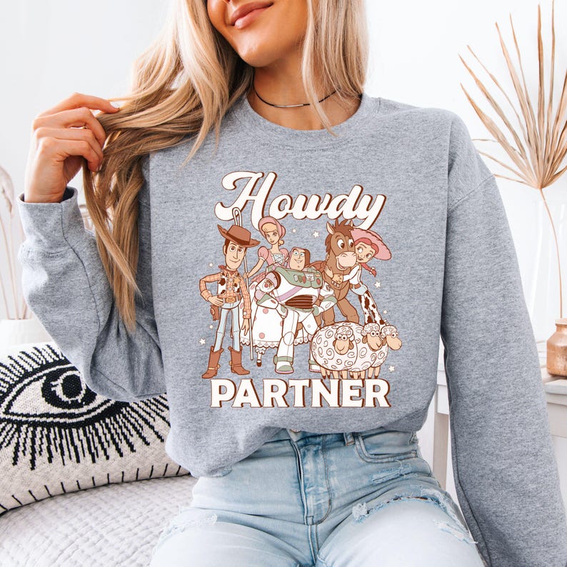 a woman sitting on a bed wearing a grey sweatshirt