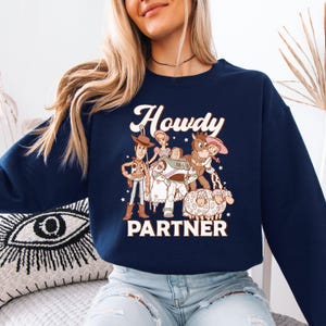 a woman sitting on a bed wearing a blue sweater