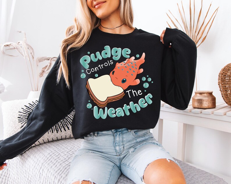 a woman sitting on a bed wearing a black sweatshirt