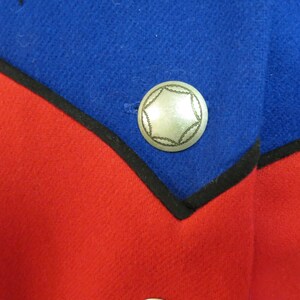 May include: A close-up of a red and blue fabric with a silver star-shaped button. The button is sewn onto the blue fabric.