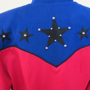 May include: A red and blue jacket with black stars and silver studs. The jacket has a pointed collar and long sleeves.