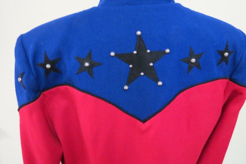 May include: A red and blue jacket with black stars and silver studs. The jacket has a pointed collar and long sleeves.