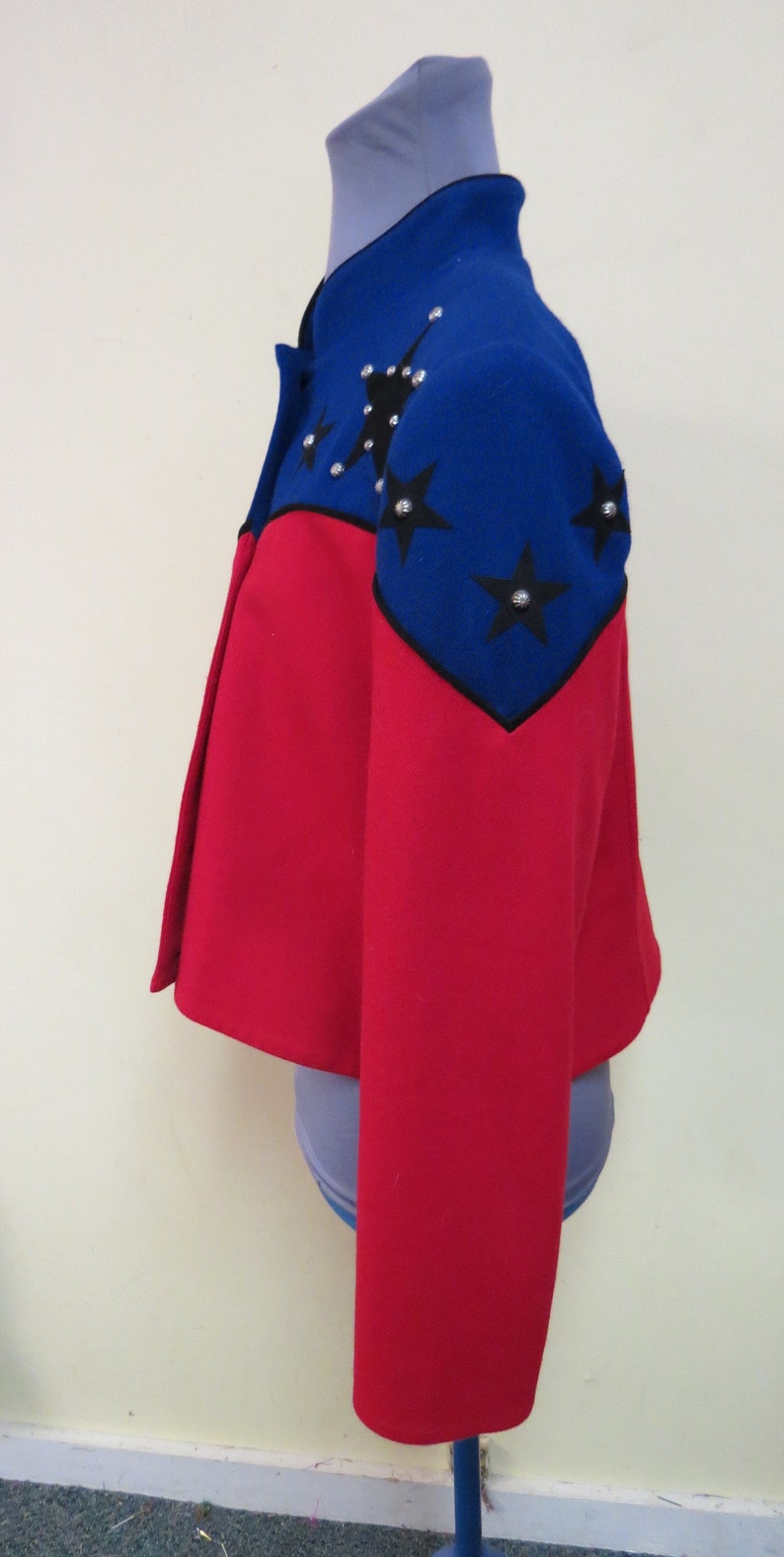 May include: A red and blue jacket with black star embellishments. The jacket has a cropped style and long sleeves.