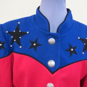 May include: A blue and red jacket with black stars and silver studs. The jacket has a mandarin collar and a button closure.