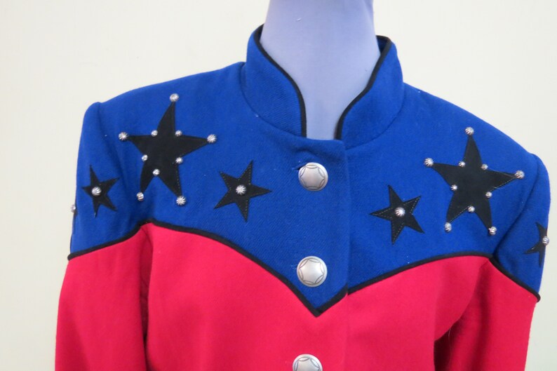 May include: A blue and red jacket with black stars and silver studs. The jacket has a mandarin collar and a button closure.