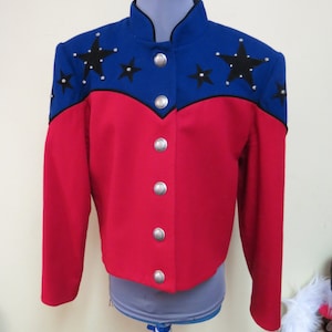 May include: A red and blue jacket with black star embellishments and silver buttons. The jacket has a stand-up collar and long sleeves.