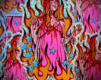Puede incluir: Una pegatina holográfica que muestra a una persona con cabello largo naranja y vestido rosa, rodeada de llamas naranjas y amarillas y estrellas azules. La persona está cubierta de líquido rojo y tiene una pequeña flor rosa en la muñeca izquierda.