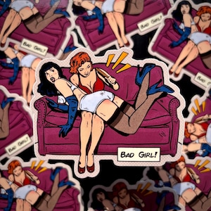 May include: A sticker featuring a retro comic-style illustration of two women on a purple couch. One woman is spanking the other with a paddle. The sticker has the words "BAD GIRL!" in a speech bubble.