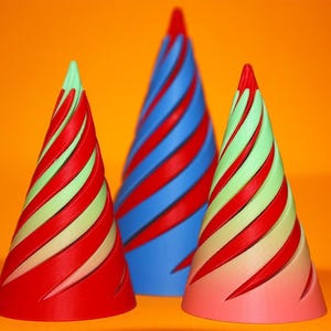 May include: Three colorful cone-shaped decorations with a spiral design. The cones are red, blue, and pink, with red and green stripes. The background is a solid orange.