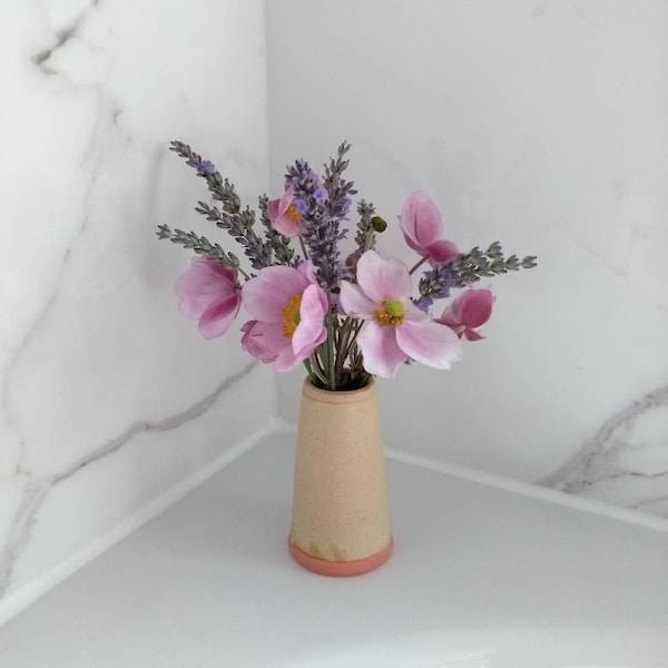 Hand thrown posy vase in an oatmeal cream glaze with pink slip highlights on the foot and rim