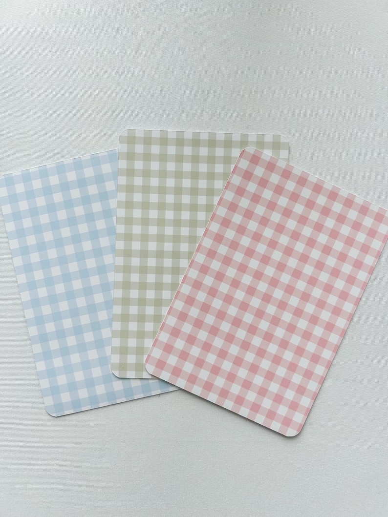 Puede incluir: Tres tarjetas rectangulares con esquinas redondeadas, cada una con un patr&oacute;n de cuadros vichy. Las tarjetas son de colores pastel: azul claro, verde p&aacute;lido y rosa. El patr&oacute;n de cuadros vichy consiste en peque&ntilde;os cuadrados espaciados uniformemente.