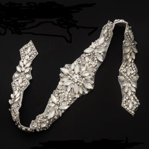 Può includere: Un bordino argentato e bianco con un motivo floreale. Il bordino è fatto di piccole perline e strass.