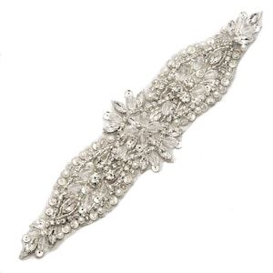 May include: A silver beaded and rhinestone trim with a floral design. The trim is approximately 12 inches long and is perfect for adding a touch of sparkle to any project.