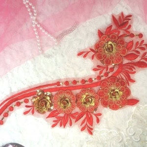 Peut inclure: Applique de broderie florale rouge et or avec des paillettes. Ce motif délicat présente une tige incurvée avec des feuilles et des fleurs.