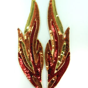 以下が含まれることがあります： 炎のデザインの、2つのスパンコールアップリケ。スパンコールは赤、金、茶色の色合いで、金のビーズの縁取りがあります。これらの対称的なアップリケは、おそらく衣類やアクセサリーの装飾用です。