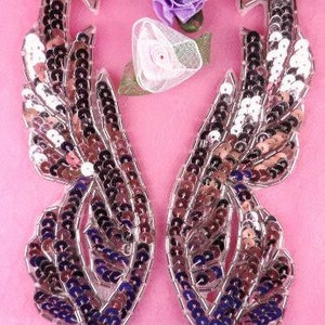 Puede incluir: Dos grandes apliques en forma de pluma, con lentejuelas y efecto iridiscente, en tonos de morado, rosa y plateado. Los apliques son perfectos para añadir un toque de brillo a la ropa, los bolsos o los proyectos de decoración del hogar.