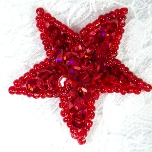 May include: A red sequined star-shaped patch with a shiny finish. The star is made of small, round sequins that are sewn together.