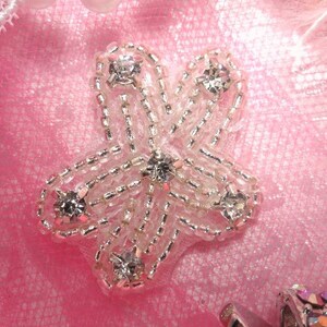 May include: A silver star-shaped embellishment with clear rhinestones on a pink fabric background.