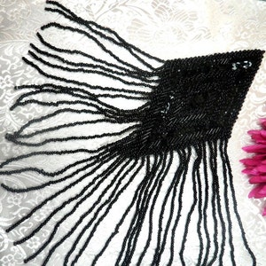 May include: Black beaded fringe trim with a diamond-shaped beaded section. The fringe is approximately 10 cm long.