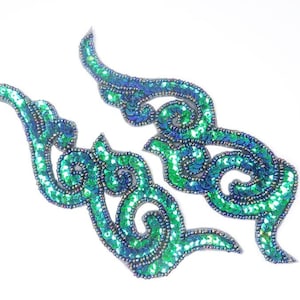 May include: Two green and blue iridescent sequined fabric appliques in a swirling, floral design.