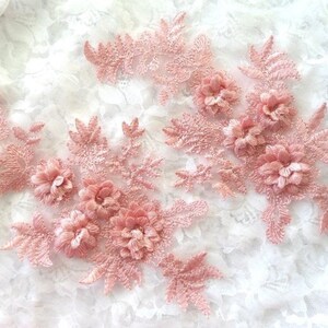 May include: Two pink floral lace appliques with delicate flower details. The appliques are perfect for adding a touch of elegance to clothing, accessories, or home decor projects.