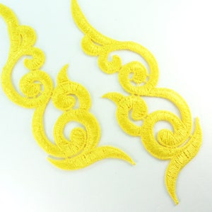 May include: Two yellow embroidered fabric appliques in a swirling, floral design.