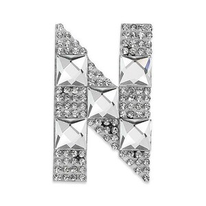 May include: A silver letter "N" embellished with clear, sparkling rhinestones and square-cut crystals. The letter is composed of alternating rows of small, round rhinestones and larger, square crystals, creating a dazzling, decorative effect.
