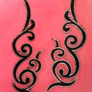 以下が含まれることがあります： 渦巻き状の花柄のデザインが施された、黒と銀の刺繍が施されたファブリックアップリケ2つ