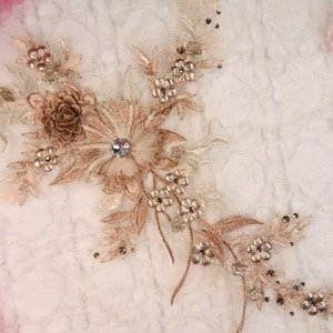 Może przedstawiać: Złota aplikacja kwiatowa z perełkami i kryształkami. Ten delikatny wzór koronki idealnie nadaje się do dodania odrobiny elegancji do odzieży, akcesoriów lub dekoracji domu.