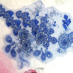 Peut inclure: Applique en dentelle florale bleue et argentée avec des embellissements perlés. L'applique présente un motif floral délicat avec des détails complexes.
