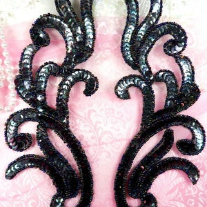 Può includere: Due applicazioni di paillettes nere e iridescenti a forma di fiore. Le applicazioni sono realizzate con piccole paillettes rotonde cucite insieme in un motivo a spirale.