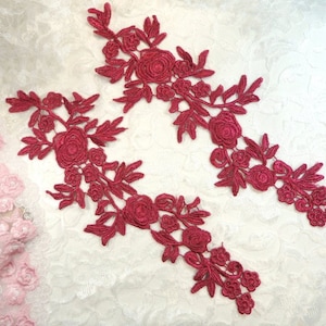 May include: Two burgundy lace appliques with floral designs. Each applique features delicate, intricate floral patterns with a raised texture.
