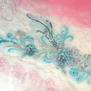 Peut inclure: Une dentelle délicate avec un motif floral brodé en turquoise et argent. La dentelle est idéale pour ajouter une touche d'élégance à n'importe quel projet.