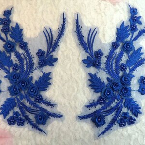 Peut inclure: Deux appliques florales bleues avec des perles. Les appliques sont en dentelle et ont un design délicat et féminin.
