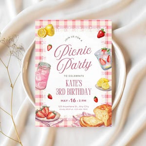 Op de afbeelding: Een picknickfeestuitnodiging met een roze ruitpatroon. De uitnodiging bevat aquarel illustraties van limonade, aardbeien en brood. Tekst luidt: "Doe mee voor een picknickfeest om Kate's 3e verjaardag te vieren, 16 mei, 15.00 uur."
