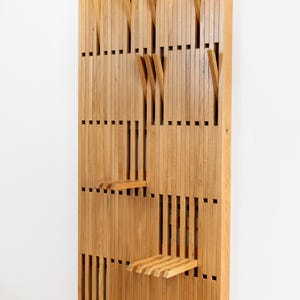 Può includere: Un appendiabiti da parete in legno con più ganci e ripiani. L'appendiabiti è realizzato in legno marrone chiaro e ha un design moderno. Il testo "HANGY" è stampato nell'angolo in alto a destra dell'appendiabiti.
