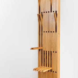 May include: A wooden coat rack with a fold-down bench. The rack has multiple hooks and the bench is made of slats. The rack is labeled "HANGY".