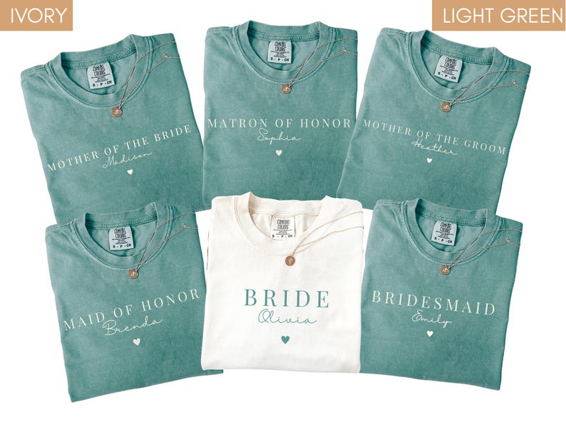 K&ouml;nnte beinhalten: Eine Auswahl an teal- und elfenbeinfarbenen T-Shirts mit goldenen Halsketten. Die teal-farbenen Shirts tragen die Aufschriften "Mother of the Bride", "Matron of Honor", "Mother of the Groom", "Maid of Honor" und "Bridesmaid". Das elfenbeinfarbene Shirt tr&auml;gt die Aufschrift "Bride".