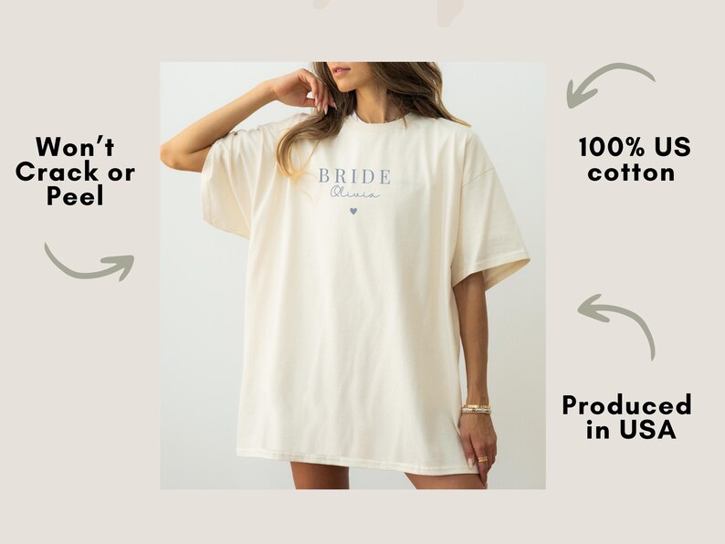 K&ouml;nnte beinhalten: Cremefarbenes &uuml;bergro&szlig;es T-Shirt mit dem Wort "Bride" und dem Namen "Olivia" in zarter Schrift sowie einem kleinen Herz aufgedruckt. Das Shirt besteht aus 100 % US-Baumwolle.