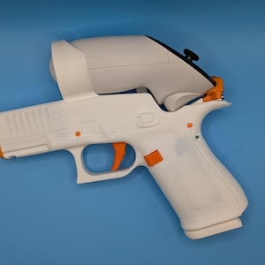 May include: A white and orange toy gun with a white attachment on top. The toy gun has an orange trigger and orange accents. The background is a solid blue.