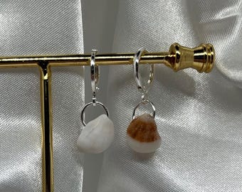 May include: A pair of silver hoop earrings with a small white and brown seashell charm hanging from each hoop.